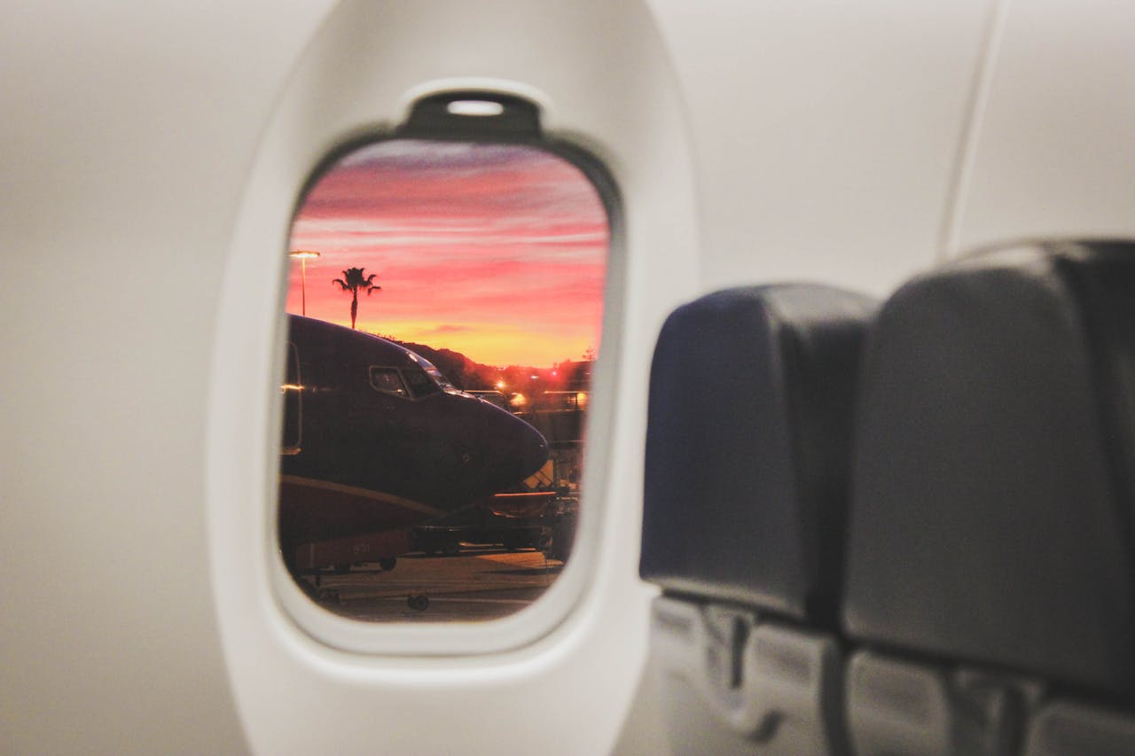 vista da janela de um avião num aeroporto ao por do sol