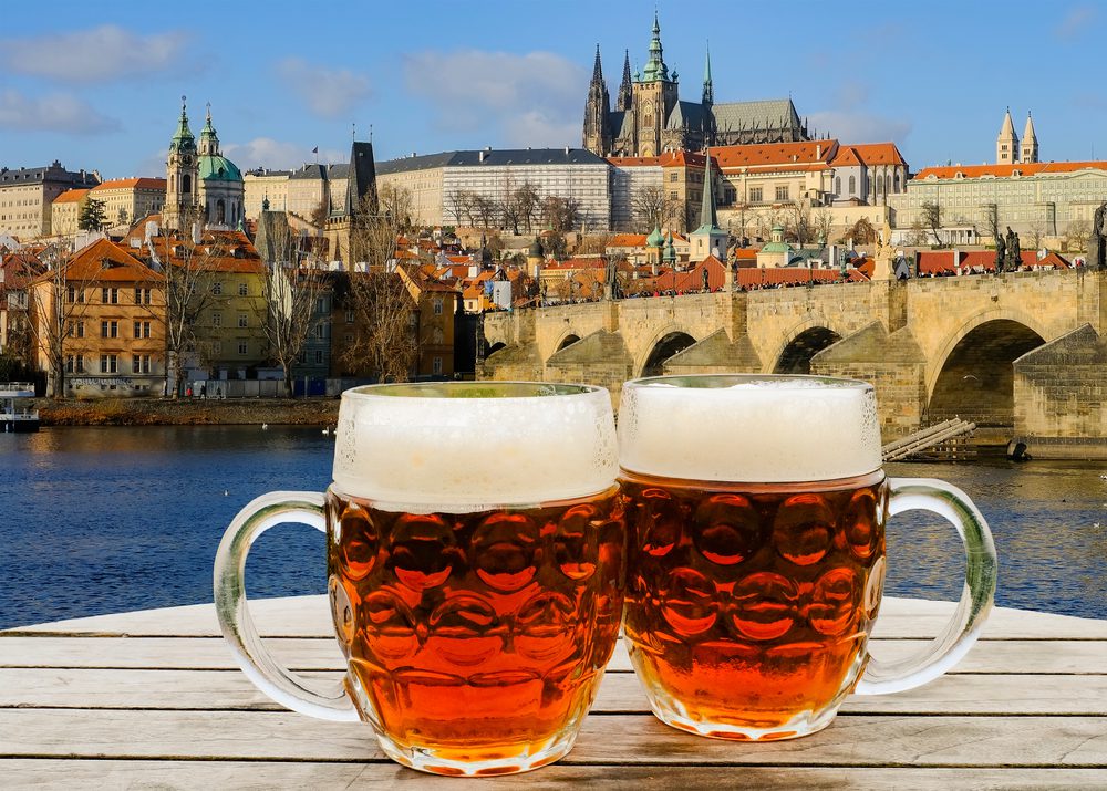 Duas canecas de cerveja com a vista de Praga no fundo